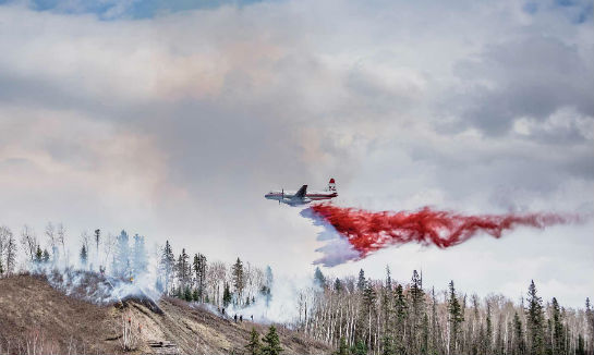 A Conair Convair CV-580 drops a load of retardant to support helitack crews working on the ground to contain a fire. Conair Photo