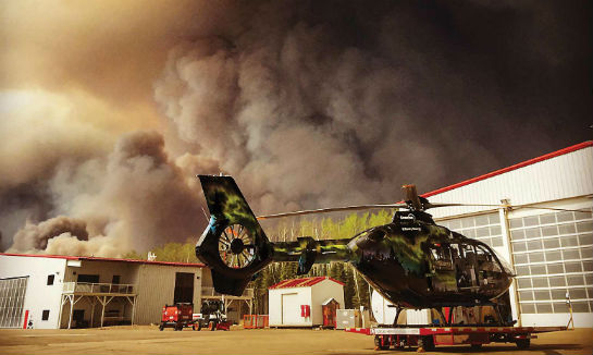 Smoke billows into the sky as fire closes in on the Phoenix Heli-Flight ramp. Remarkably, the company's facilities sustained little damage. Ryan Tyler Photo